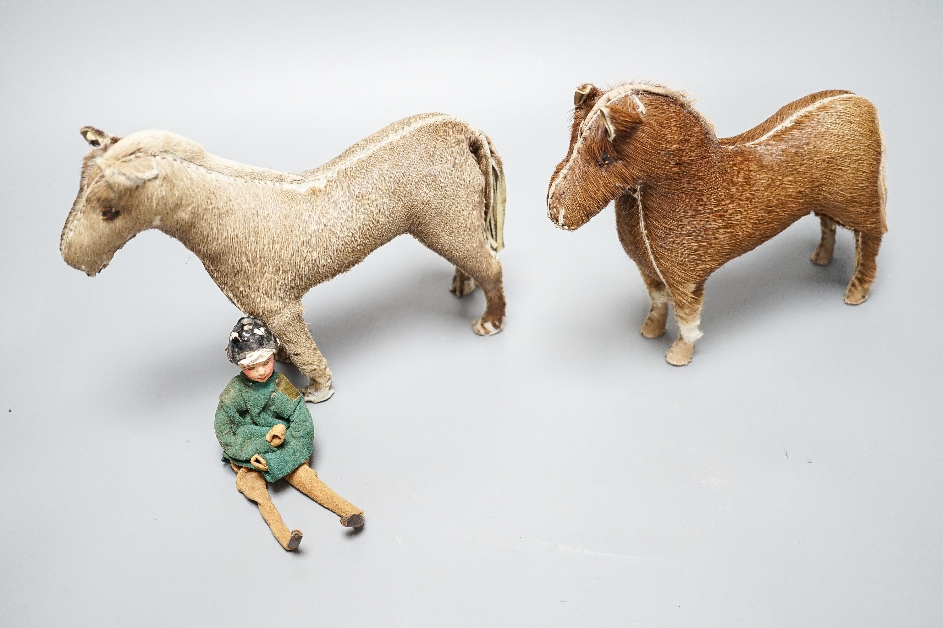 Two Edith Reynolds handmade real skin and leather horse models, 18cm high, together with a female jockey and related leather accessories
